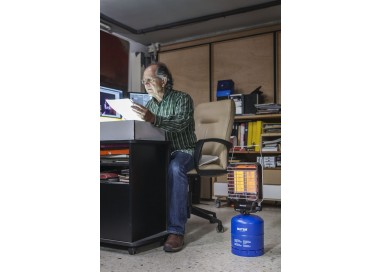 Persona utilizando la estufa Butsir en escritorio para calefacción de interior ventilado