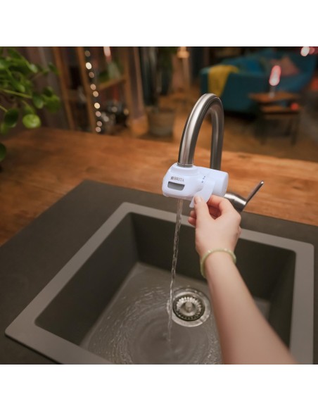 Imagen de cocina con el sistema de filtro BRITA ON TAP instalado en el grifo con agua corriendo